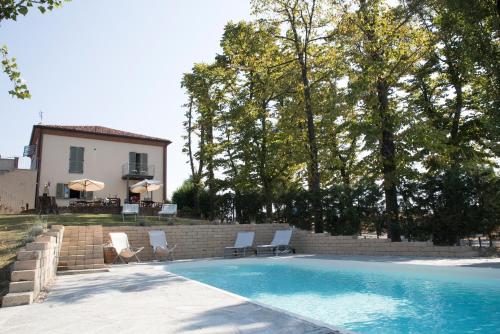 a swimming pool with chairs and a house at Casa Vacanze San Stefanetto in Treiso