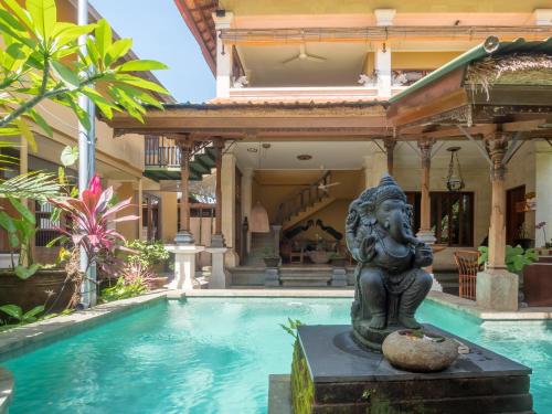a statue in front of a house with a swimming pool at Maruti Lane Villa in Ubud