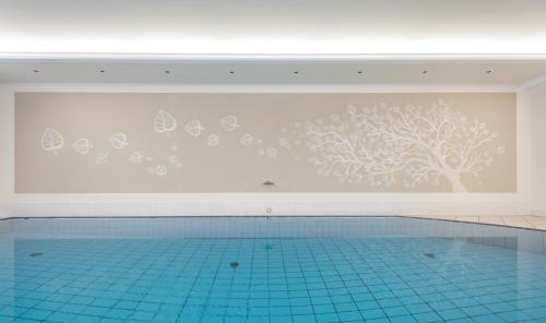 basen ze ścianą z malowidłem drzewnym w obiekcie Park Hotel Bellevue w mieście Dobbiaco