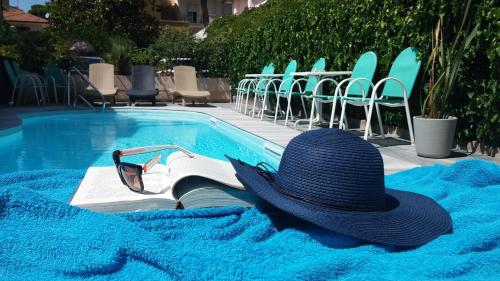 un sombrero y un libro junto a una piscina en Hotel Condor-New 2024-Con Piscina, en Riccione