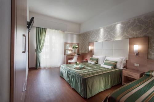 a hotel room with a bed with a green bedspread at Michelangelo Cesenatico in Cesenatico