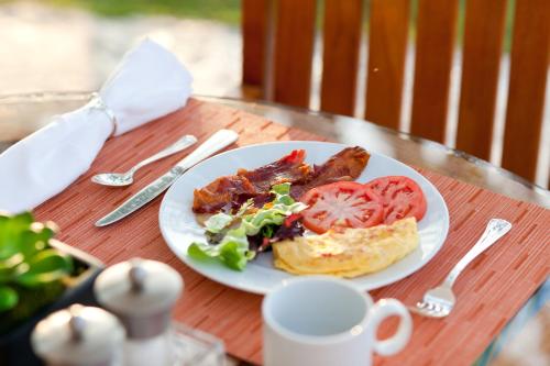 un plato de comida con tocino y tomates en una mesa en Motel Alibi en Banja Luka