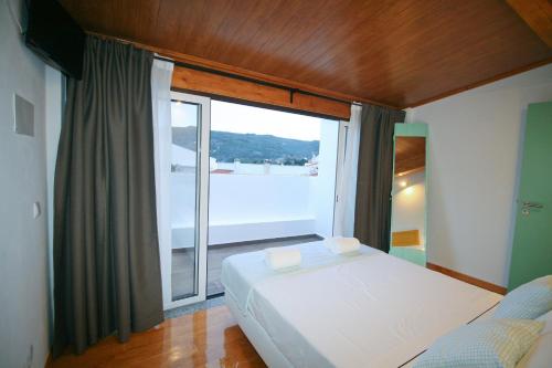 a bedroom with a bed and a large window at Casa dos Batalim in Monchique