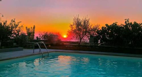 une piscine avec vue sur le coucher du soleil en arrière-plan dans l'établissement Zephyros Rooms And Apartments, à Drymon