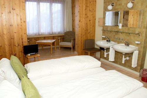 a bathroom with a bed and a sink and a mirror at Chamanna Bed & Breakfast in Arosa