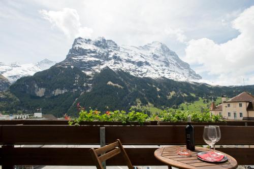 a table with a glass of wine and a mountain at Hotel Bernerhof Grindelwald in Grindelwald