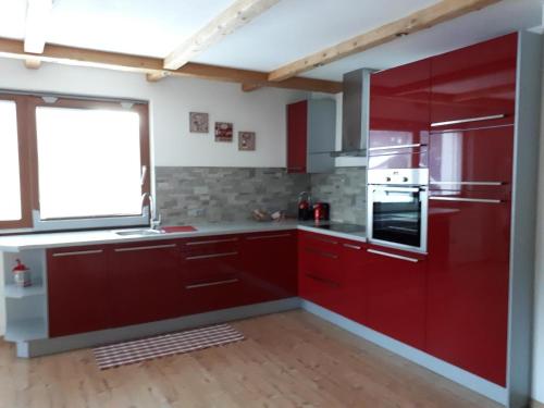 cocina con armarios rojos y ventana grande en casa Lory en Vigo di Fassa