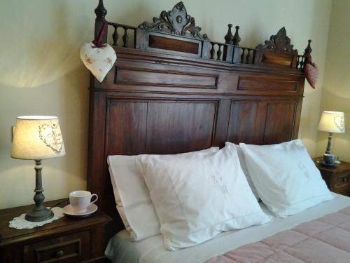 a bed with a wooden headboard and white pillows at B&B Casa Dolce Casa in Candelo