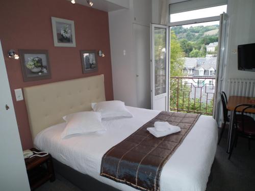 a bedroom with a large bed and a balcony at Hôtel de l'Aviation in La Bourboule