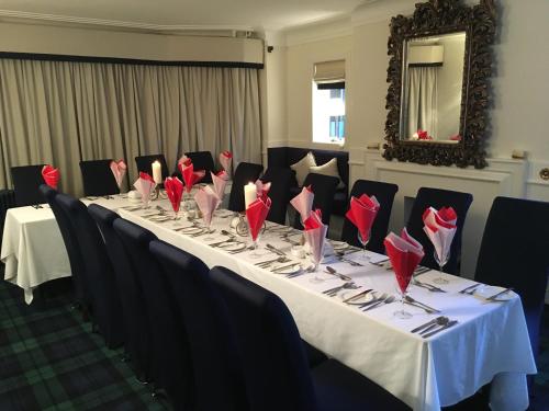 un lungo tavolo con tovaglioli rossi sopra di Crookston Hotel a Glasgow