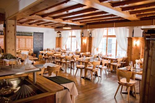 a restaurant with wooden tables and chairs and windows at Chamanna Bed & Breakfast in Arosa
