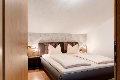 a bedroom with a large bed with white sheets and pillows at Appartementhaus Bergland in Obsteig