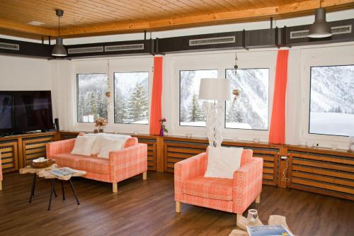 a living room with two chairs and a tv at Chamanna Bed & Breakfast in Arosa