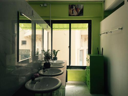 a row of sinks in a bathroom with green walls at Colombo Downtown Monkey Backpackers Hostel in Colombo