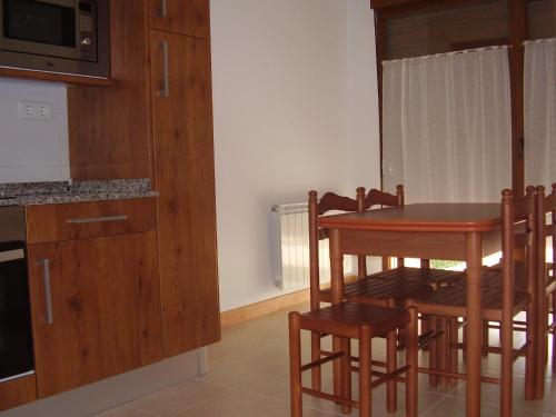 een keuken met een tafel en stoelen en een magnetron bij La Pergola in Santillana del Mar