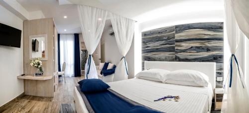 サン・ヴィート・ロ・カーポにあるIl Mare Dentro Roomsの白いベッド1台付きのベッドルーム1室(壁に絵画付)