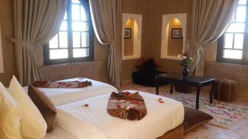 two beds in a room with two windows at Kasbah ATFEL in Ourika