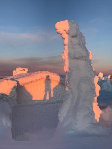 a man standing on top of a snow covered mountain at Hakamajat Cottages in Syöte