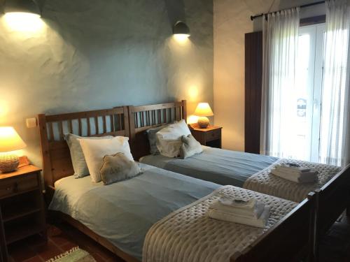 a bedroom with two beds and two lamps and a window at Herdade Do Freixial - Turismo Rural in Vila Nova de Milfontes