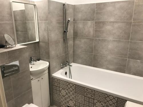 La salle de bains est pourvue d'une baignoire, d'un lavabo et de toilettes. dans l'établissement Sportowy Apartament nad Jeziorem, à Olsztyn