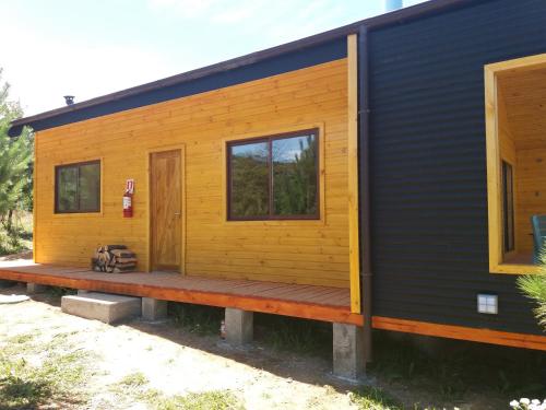 a tiny house with a black and yellow exterior at Cabañas Rincon del Sur in Cochrane
