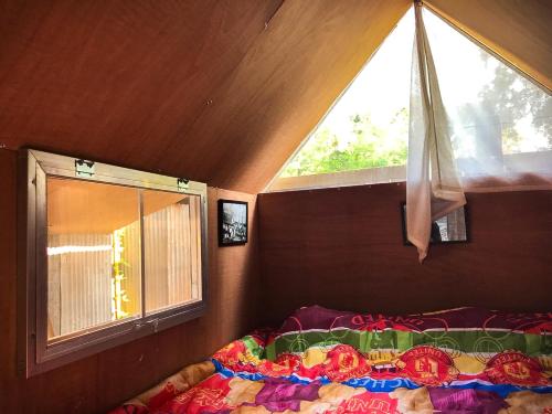 een slaapkamer met een raam en een bed met een dekbed bij KhonThao in Lamphun