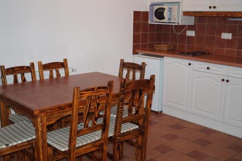 - une cuisine avec une table en bois, des chaises et un four micro-ondes dans l'établissement Emanapartmanok Sárvár, à Sárvár