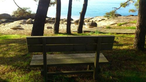 a wooden bench sitting on the grass near the ocean at Hotel Torres Touriño in Sanxenxo