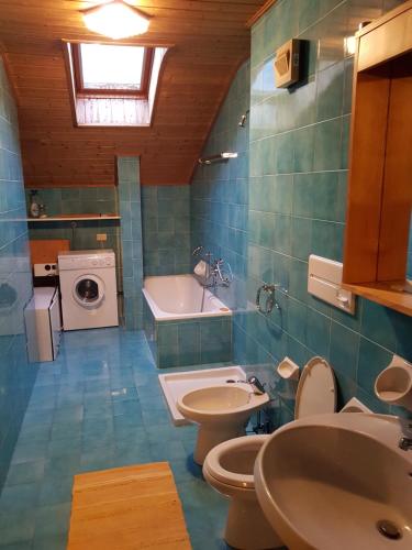 een badkamer met 2 toiletten, een wastafel en een wasmachine bij Ortisei - Nel cuore delle Dolomiti in Ortisei