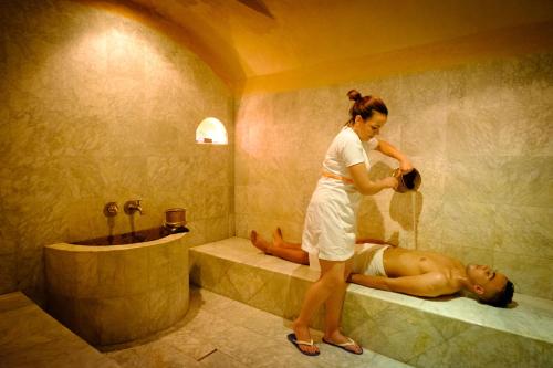 uma mulher numa casa de banho com um homem deitado numa banheira em Riad Tafilalet em Fez