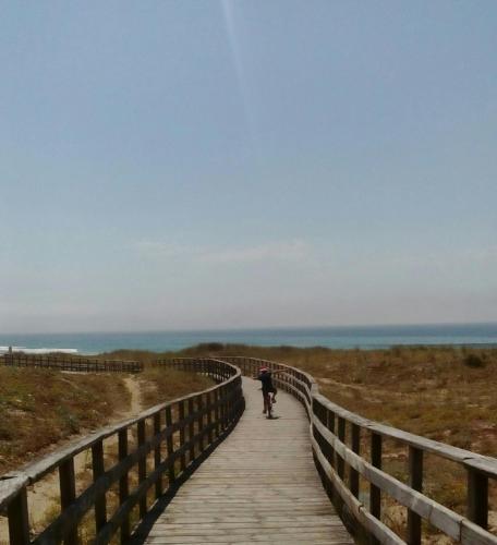 a person riding a bike on a boardwalk on the beach at Hotel Torres Touriño in Sanxenxo
