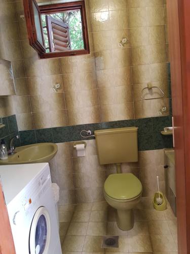 a bathroom with a toilet and a sink and a washing machine at Apartment Slava in Primošten