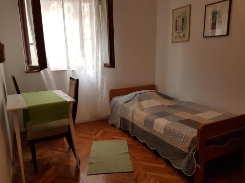 a bedroom with a bed and a desk and a window at Apartment Slava in Primošten