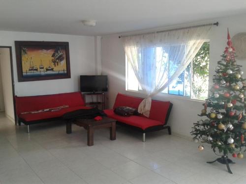una sala de estar con un árbol de Navidad y un sofá rojo en Casa de Campo Palmarito, en Tubará