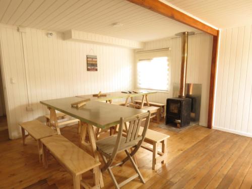 a room with a table and chairs and a stove at Quilda Hostel in Hornopiren