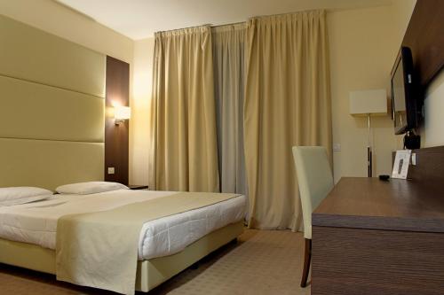 フィアーノ・ロマーノにあるPalace Inn Rome Fianoのベッドとデスクが備わるホテルルームです。