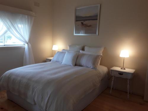 ein Schlafzimmer mit einem großen weißen Bett mit zwei Lampen in der Unterkunft Bay Bell Cottage in Saint Leonards