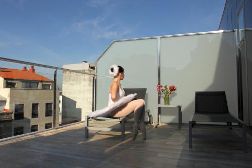 a woman sitting on a chair on a balcony at Agua de Mar Hotel Boutique in Vigo