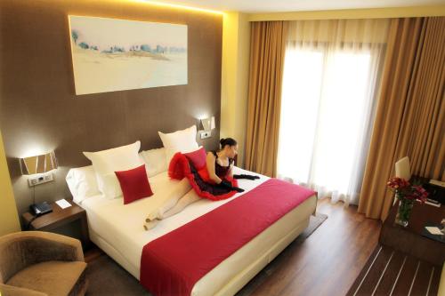 a woman sitting on a bed in a hotel room at Agua de Mar Hotel Boutique in Vigo