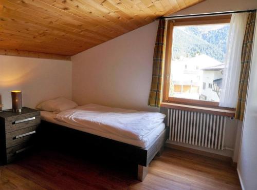 ein kleines Schlafzimmer mit einem Bett und einem Fenster in der Unterkunft Ulrike (709 Sh) in Lenzerheide
