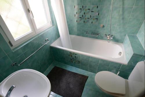a bathroom with a toilet and a tub and a sink at Oreas (724 Du) in Valbella
