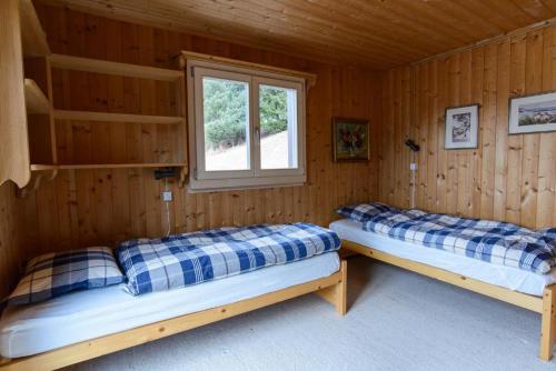 two beds in a log cabin with a window at Oreas (724 Du) in Valbella