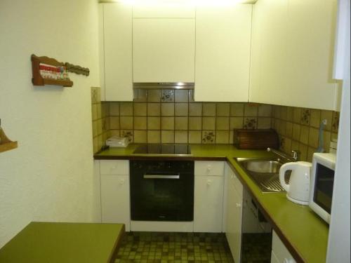 eine kleine Küche mit weißen Schränken und einem Waschbecken in der Unterkunft La Schmetta 5 (334 Fo) in Lenzerheide