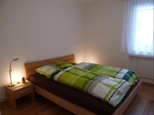 ein Bett mit einer grünen und weißen Bettdecke in einem Schlafzimmer in der Unterkunft Sil Bot (220 Kn) in Lenzerheide