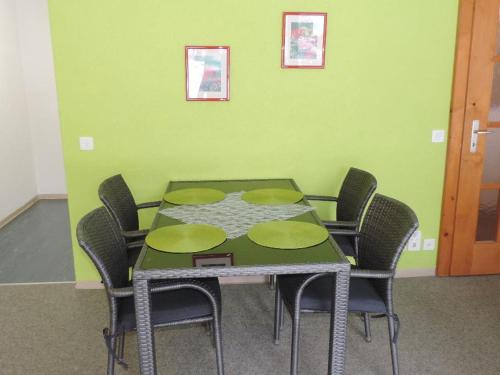 a dining room table with chairs and a green wall at Gentiana (162 Li) Studio in Valbella