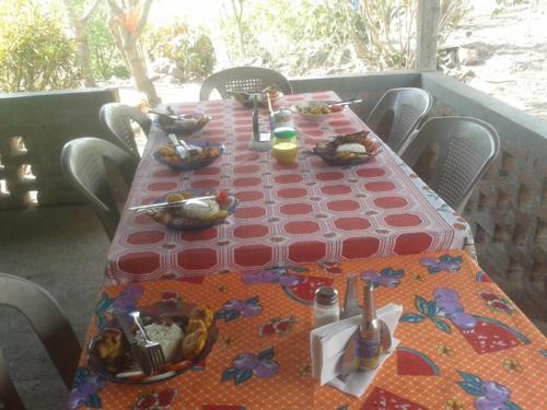 a table with a red table cloth with food on it at La Ceibita Tours in Los Potrerillos