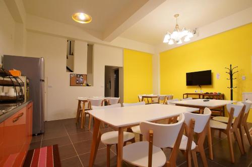 a dining room with tables and chairs and a tv at Trip Village-Hulk's Homestay in Taitung City