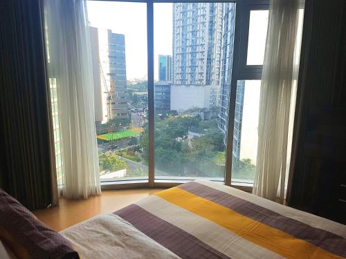 a bedroom with a bed and a large window at Avant Apartments at The Fort in Manila