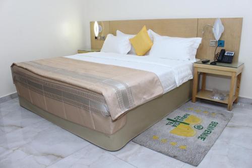 een groot bed in een hotelkamer met een tafel bij Paradisia Hotel in Cotonou