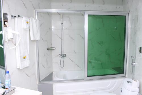 a bathroom with a shower with a glass door at Paradisia Hotel in Cotonou